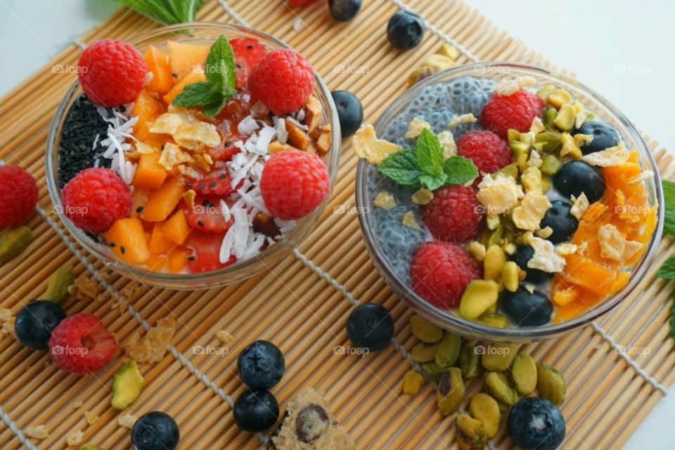 Healthy Fresh Fruit Smoothie Bowl - creamy raspberry smoothie topped with peach, seeds, dry coconuts,  nuts, blueberry and strawberry