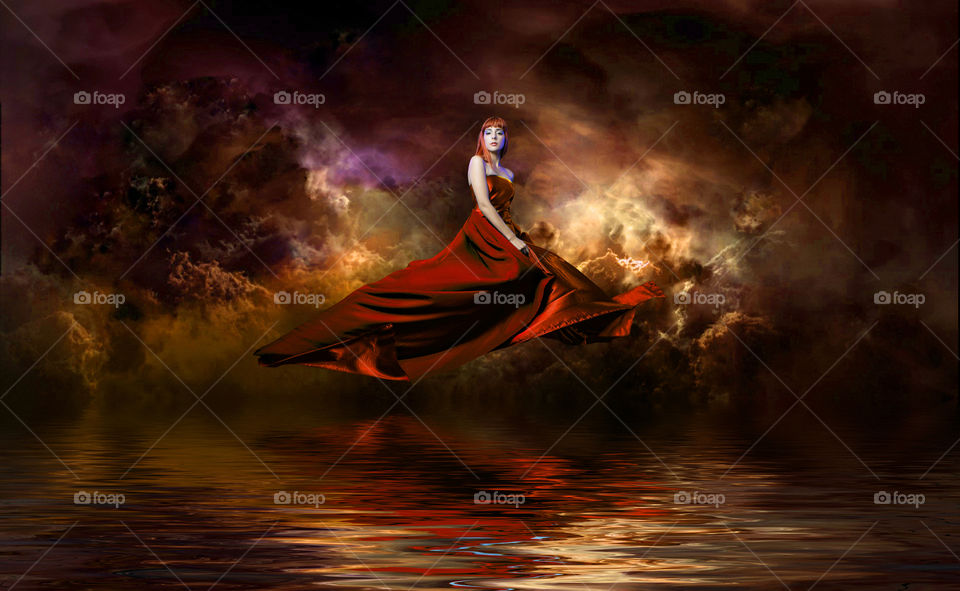 Girl with red dress floating over water