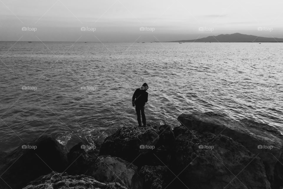 Silhouette of a man stood on the rock, welcoming the morning sun on the beach, a fresh air before the sun rises