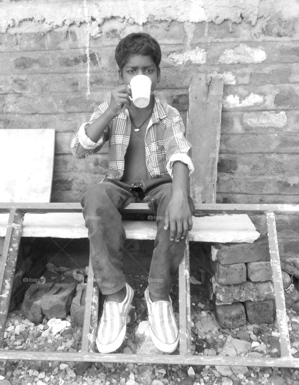 Photo of a boy drinking tea / A photo of a boy / A boy drinking tea from the mug / Photo of an Indian boy drinking tea / Photo of a boy/Photo of a poor boy / a poor boy sitting / drinking tea from a poor boy big mug