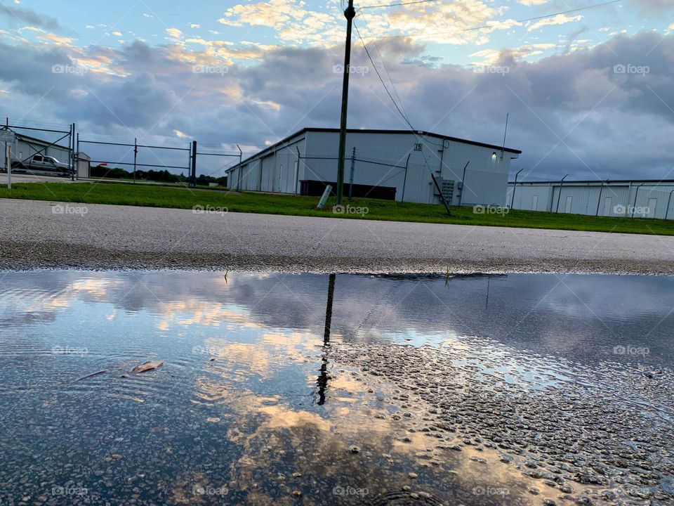 At An Airport Street After The Rain With Sky Reflection On On The Puddle.