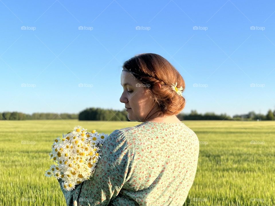 Summer portrait of a woman with a bouquet of wild daisies