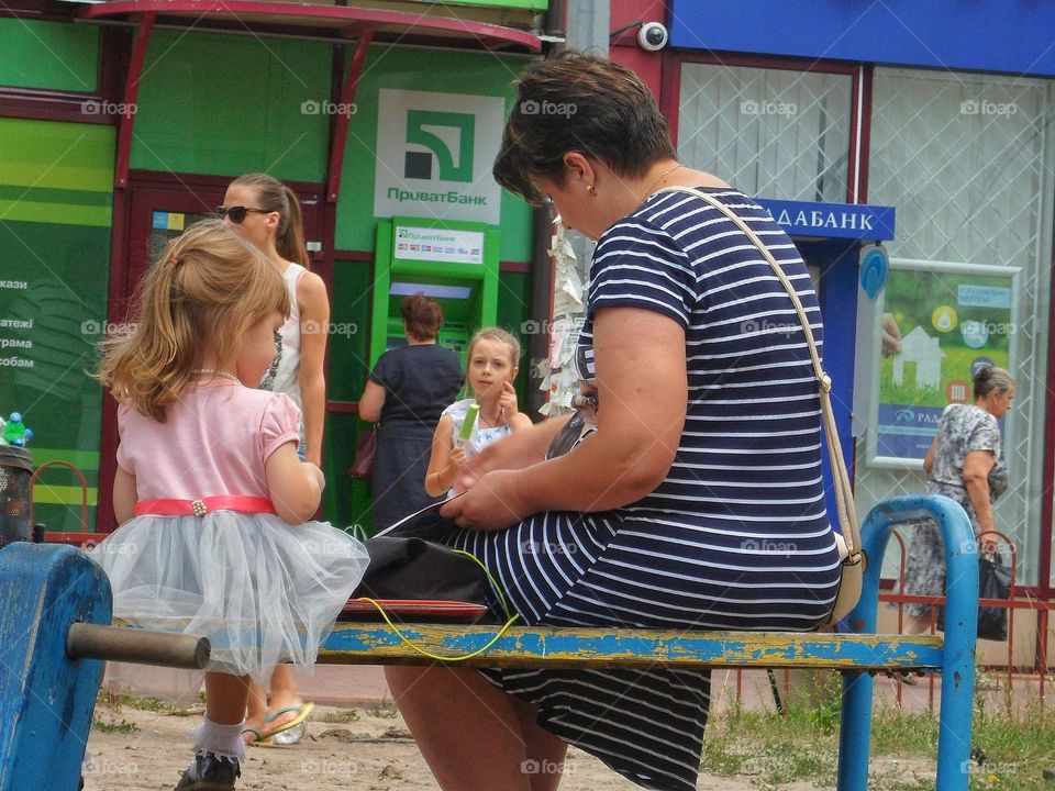 mother sits with her daughter on a bench