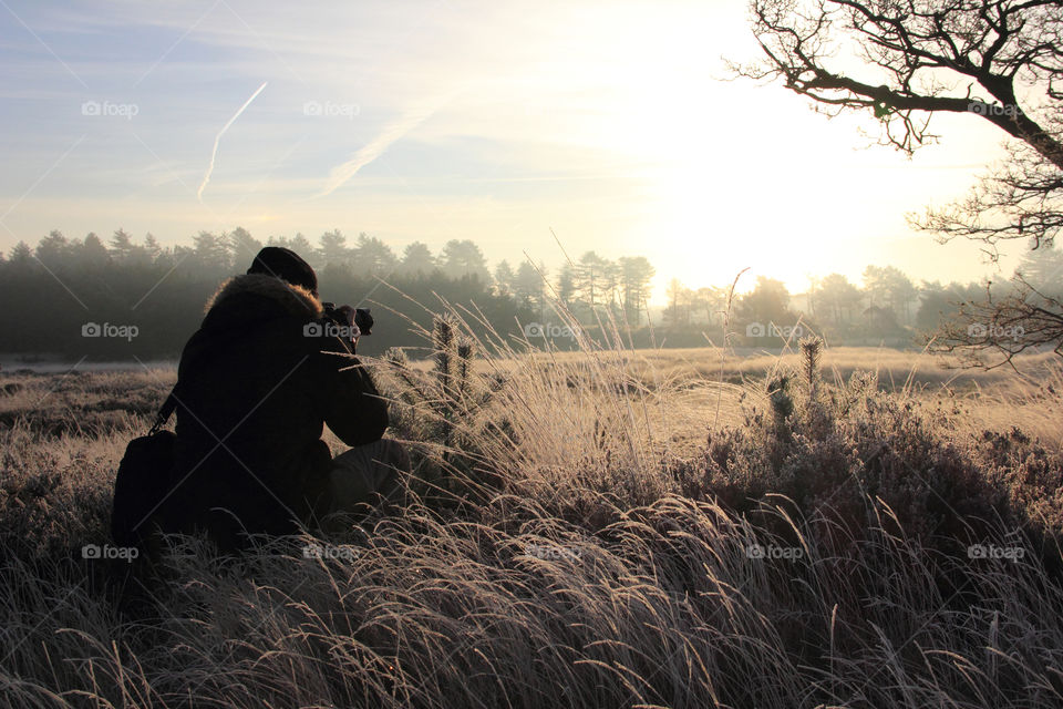 A photographer sitting in a meadow, with his camera at the ready to take the shot of the meadow at golden hour. It truly was a beautiful sight.