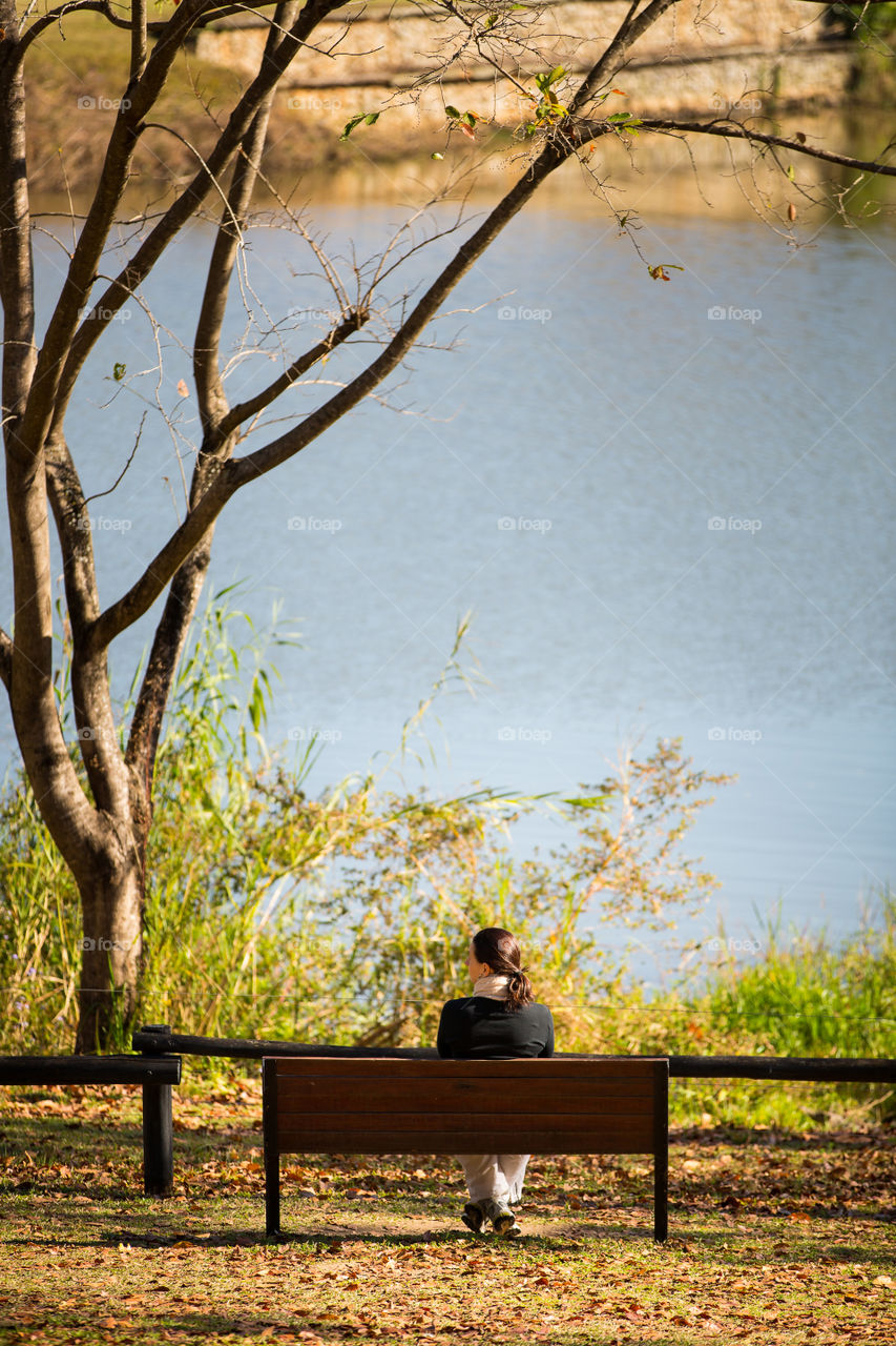 Wind down and relax in the fresh air and beautiful outdoors. Image of woman on a bench relaxing at a scenic lake