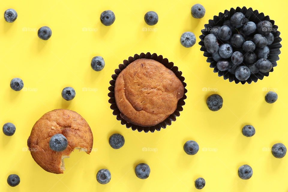 Muffins and blueberries on yellow
