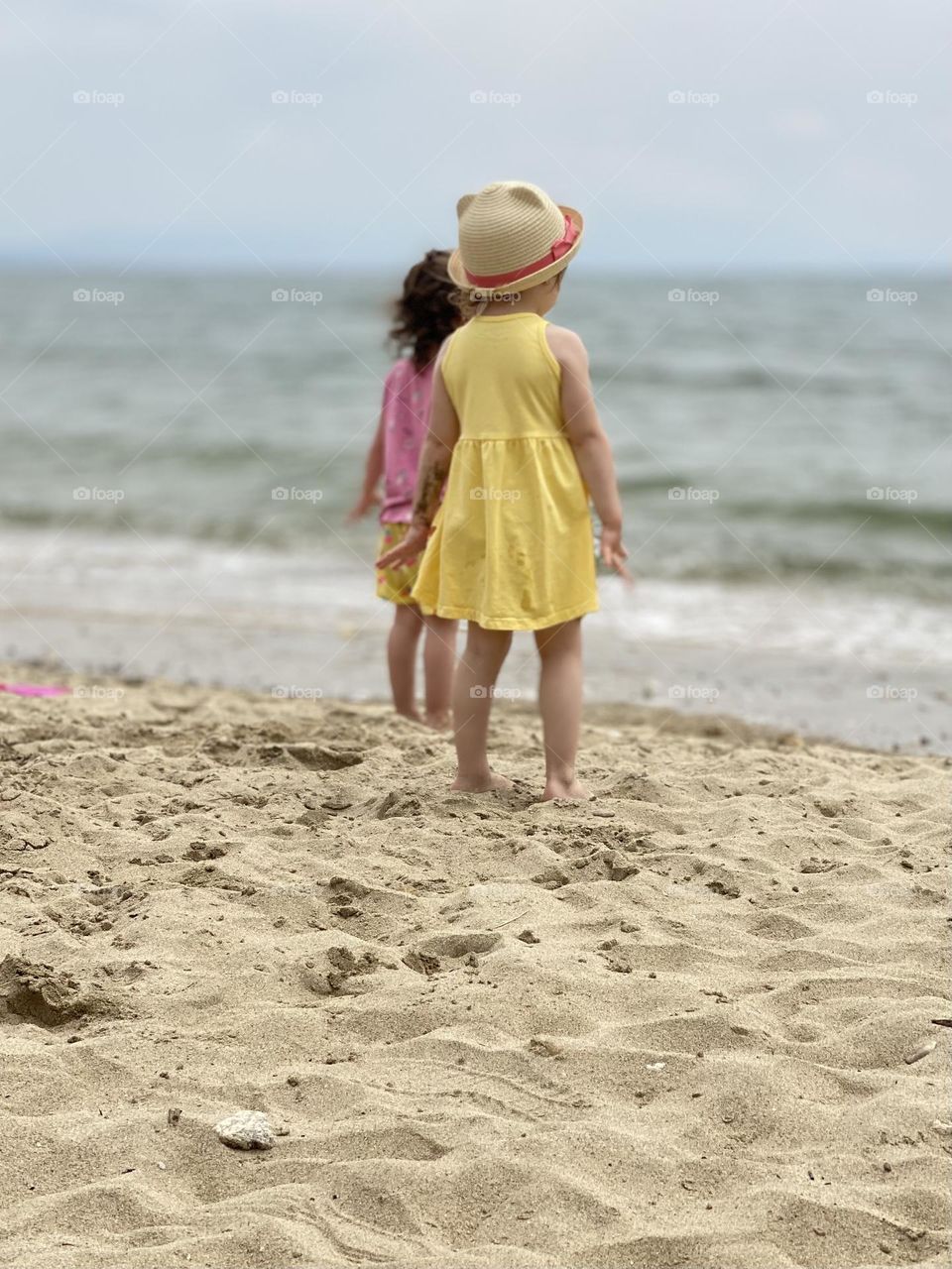 Back view of two little girls on the beach 
