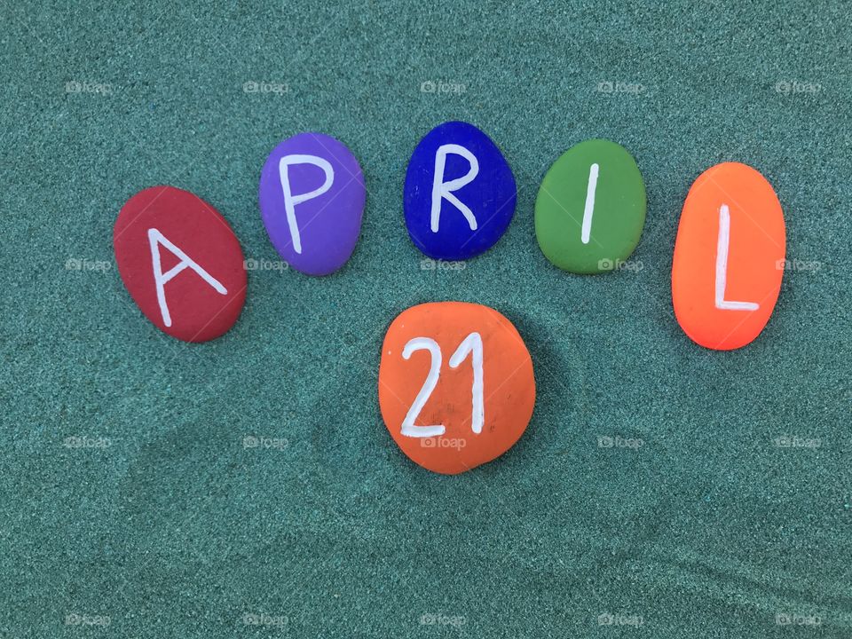 21 April, calendar date with colored stones over green sand 