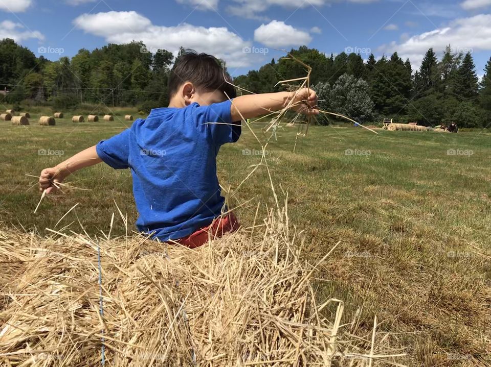 Young boy playing with a hay bail