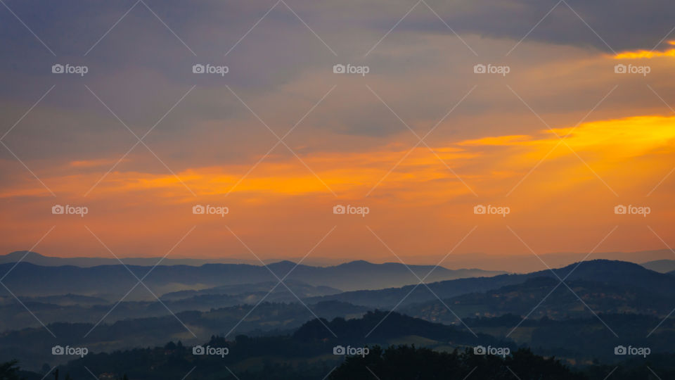 Orange clouds over bluish fields in West Serbia