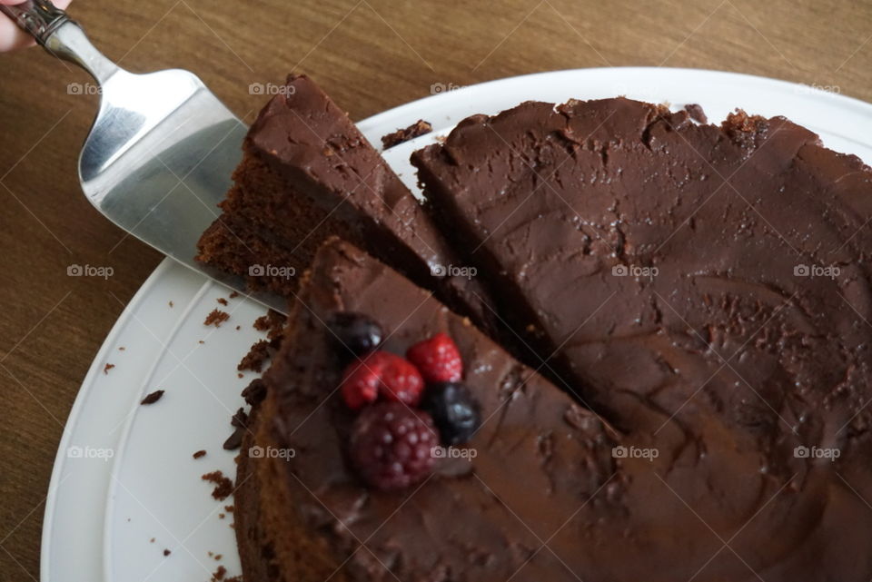 A layered chocolate cake topped with a berry garnish. 