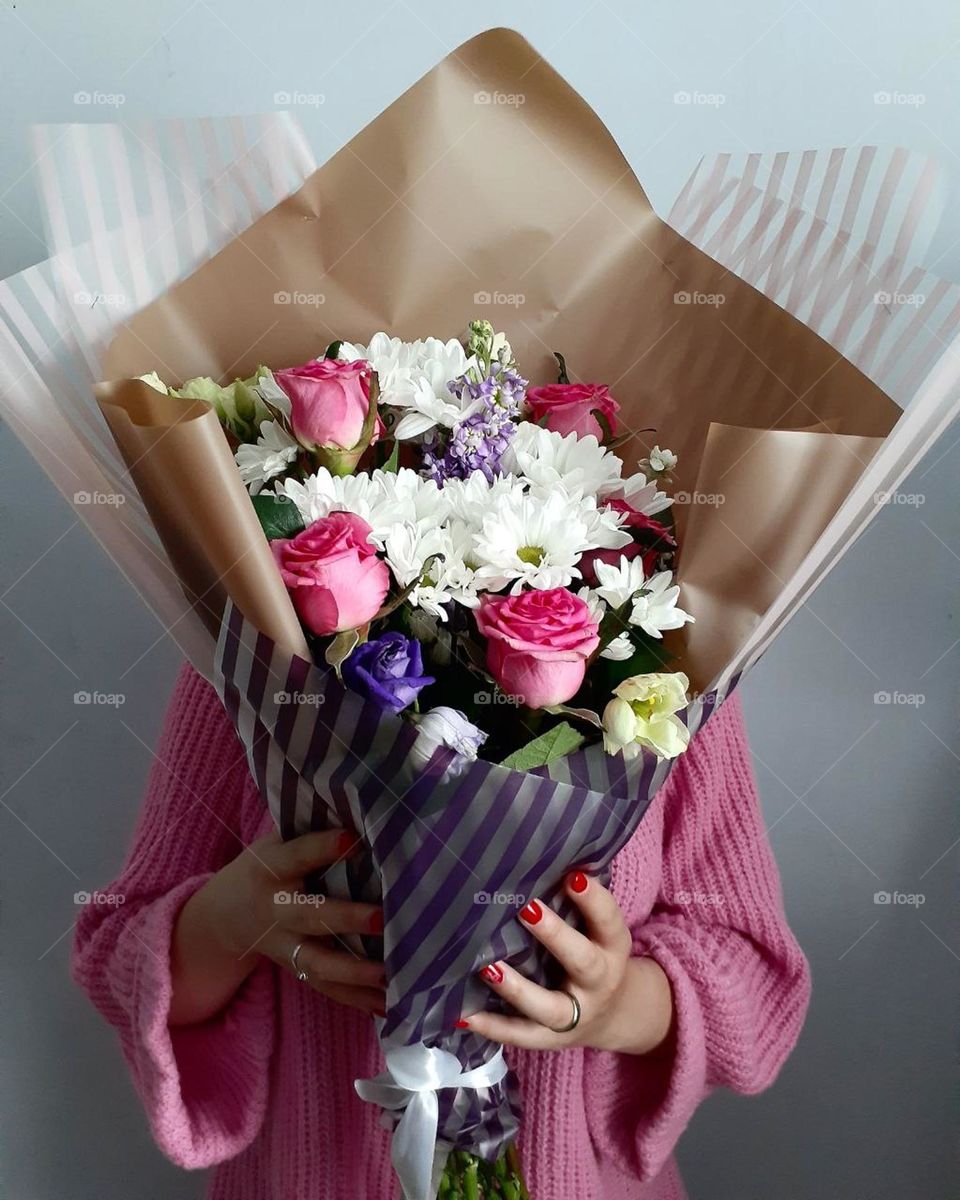 A girl in a pink jacket is holding a bouquet of flowers