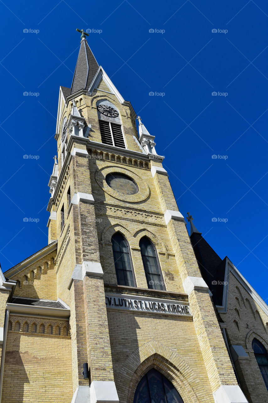 Cream city brick church spire against a blue sky