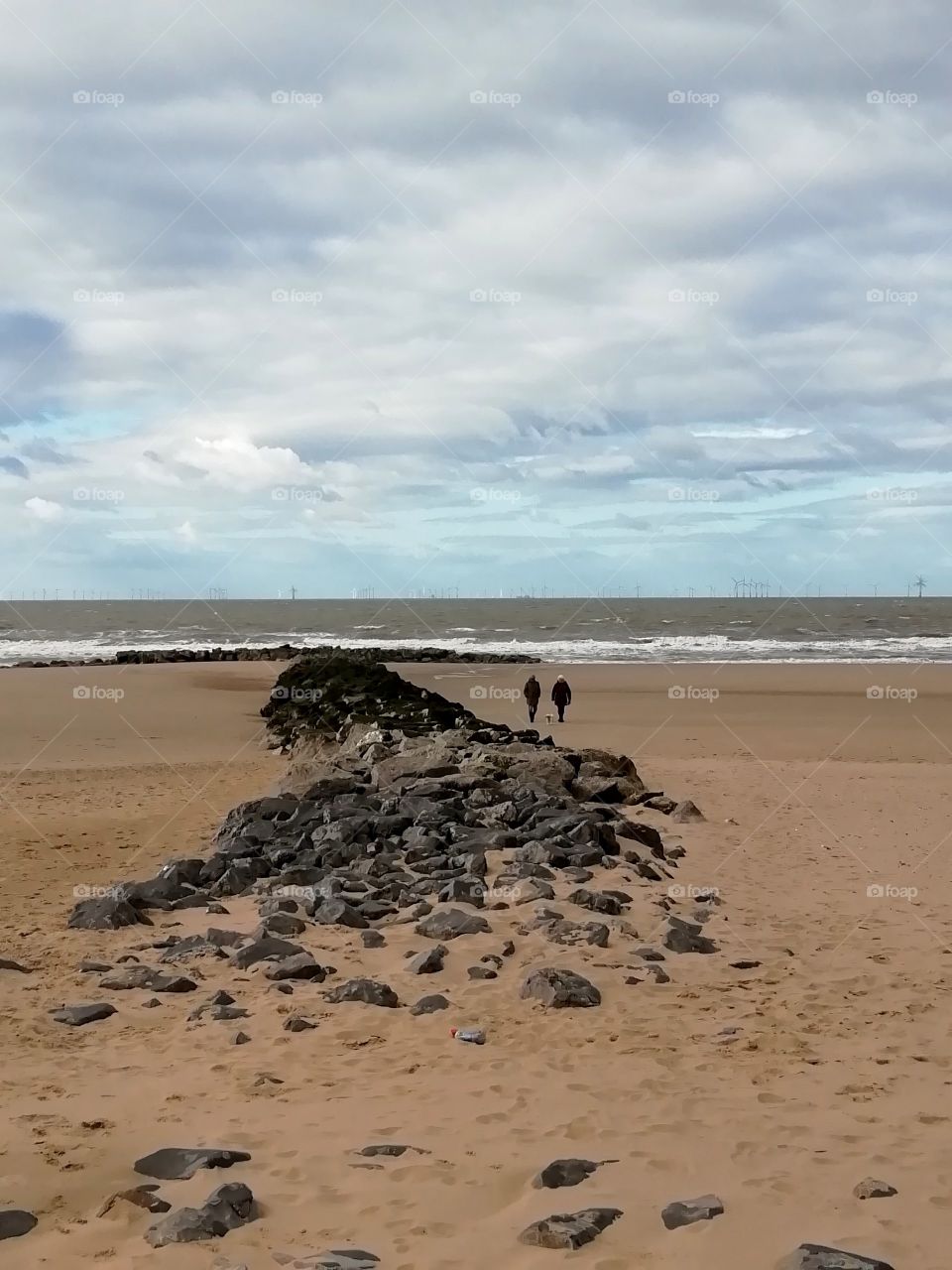 Rocks on a sandy beach against a cloudy sky