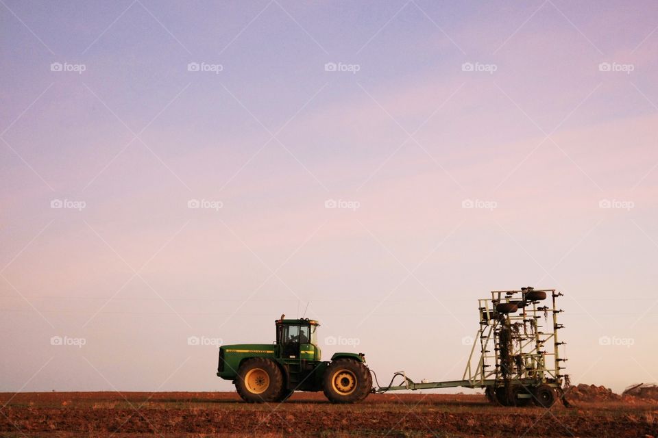air seeder and centre pivot John Deere tractor in a paddock at dusk in rural Western Australia
