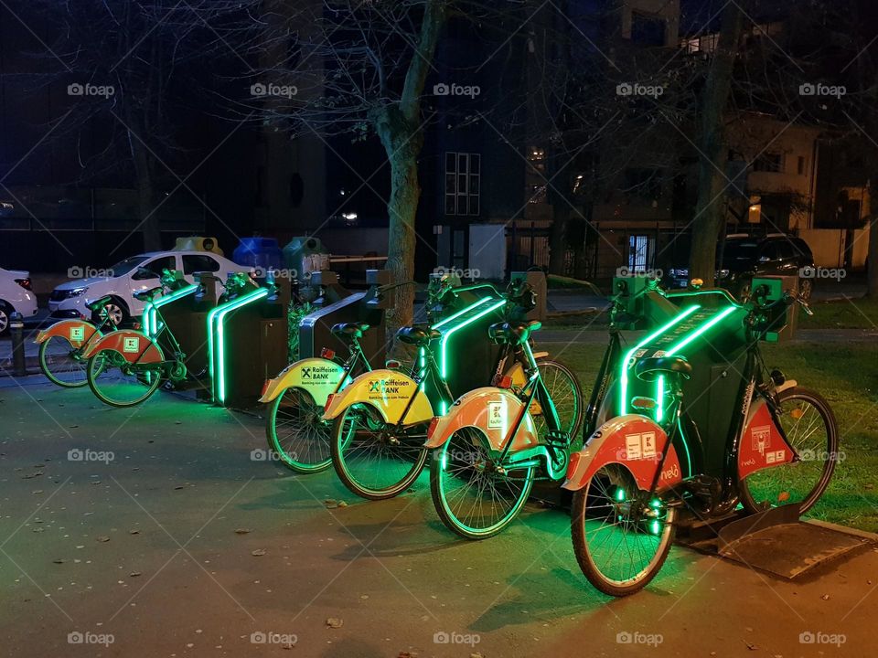 Colorful bicycles in a row in a lit bicycle stand