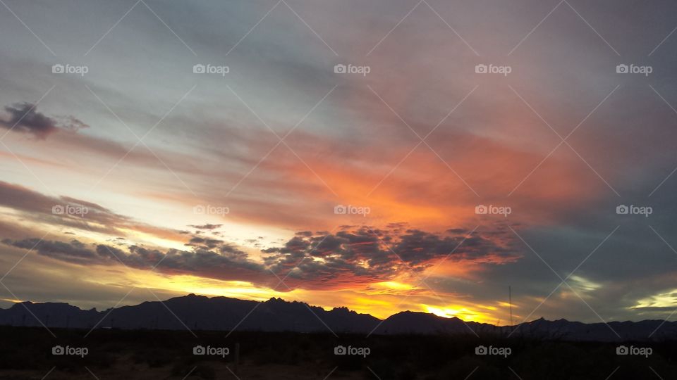 Sunset over mountains glowing orange red and yellow with clouds
