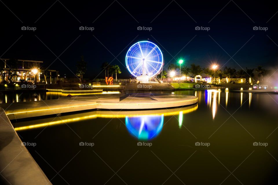 The night view of a lake in the city of Surabaya shows the reflection of light from the Ferish Weel