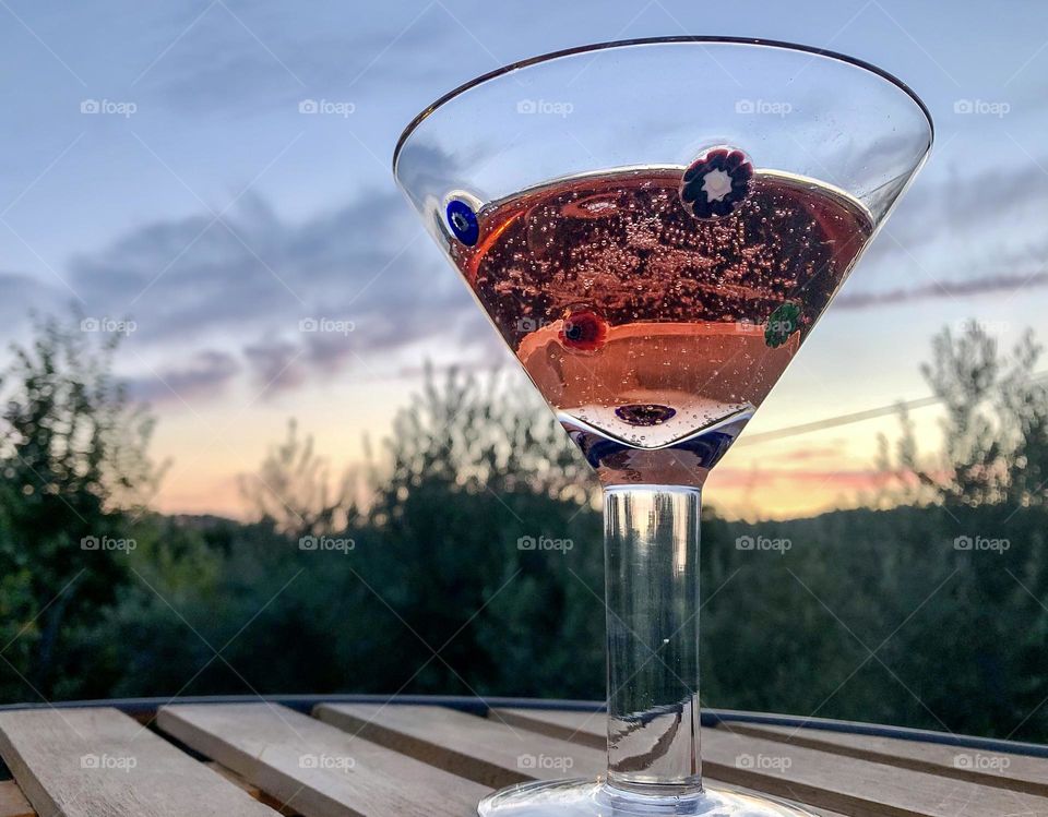 A glass of pink fizz at sunset