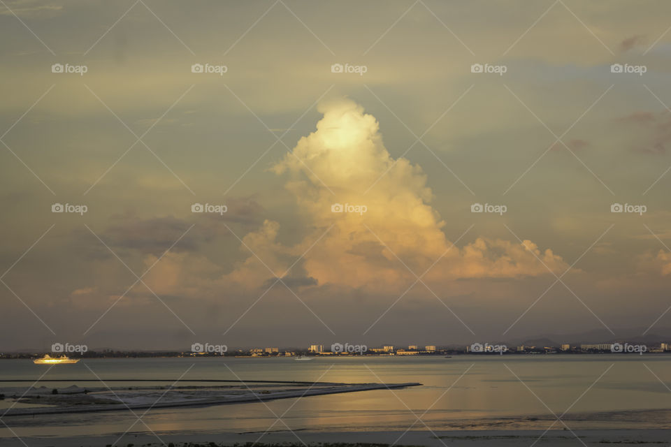 Golden light reflects on clouds and water.