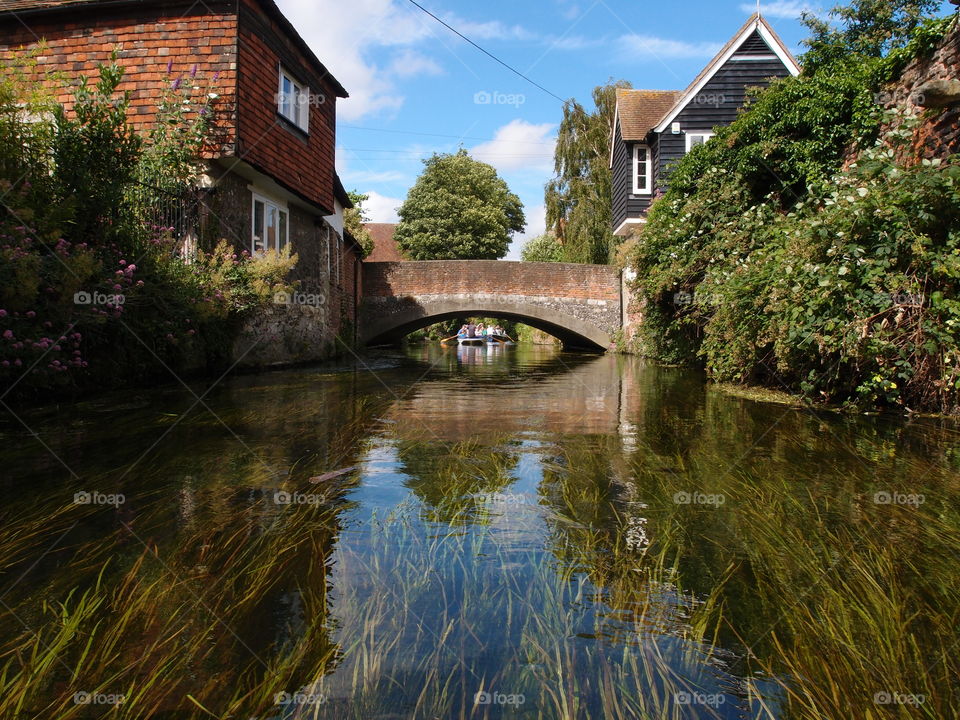 During a boat tour the York River in England flows under brick bridges and buildings on a summer day 