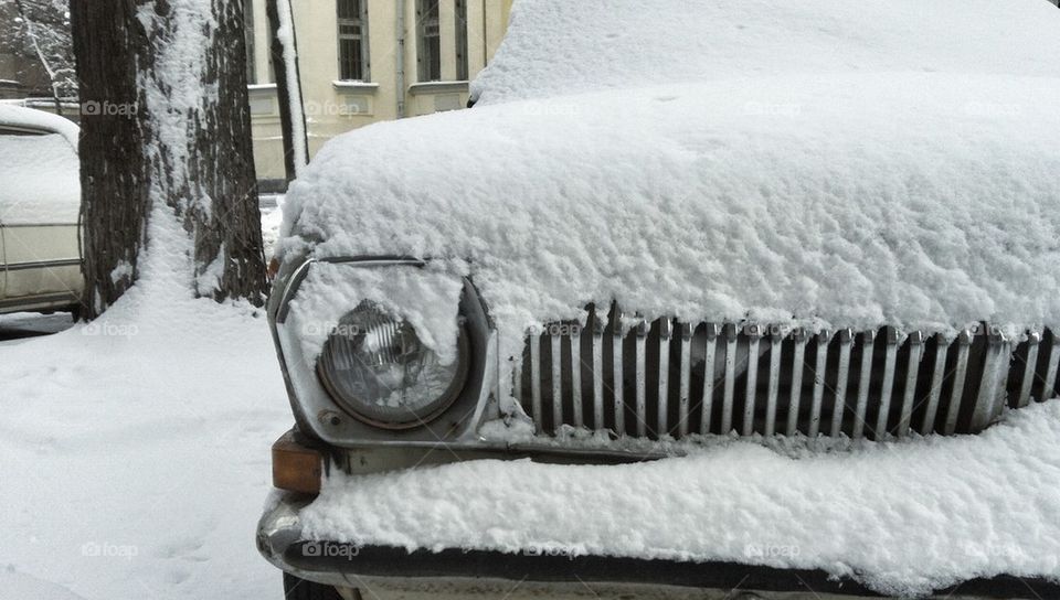 Snow-capped soviet car on winter street. Radiator grill 