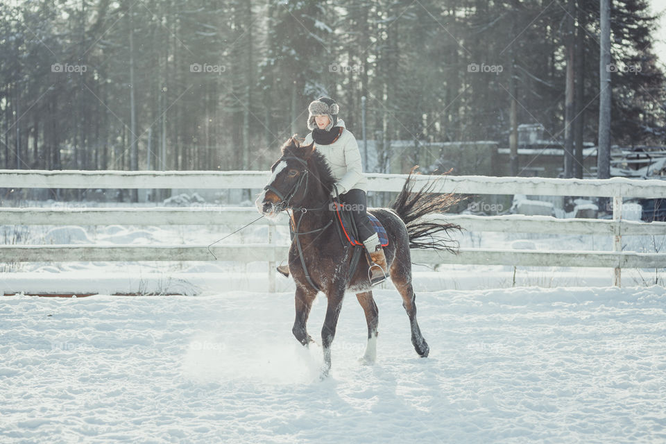 Teenage girl horseback jumping at cold winter day 