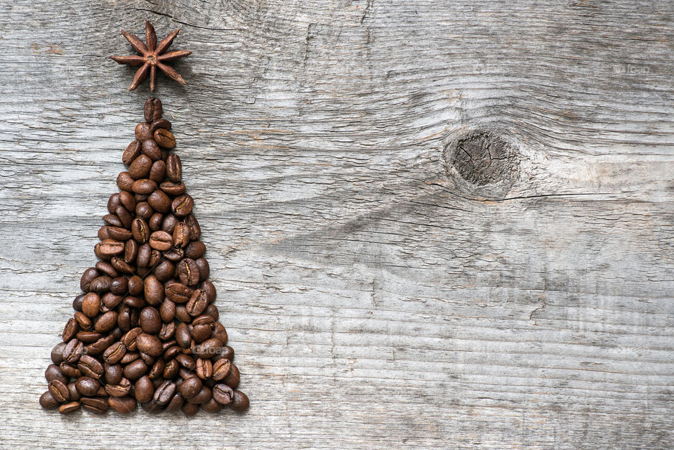 Christmas greeting card made of coffee beans on old wooden background