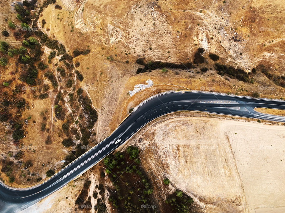 Aerial view of a tiny car moving by the open road 