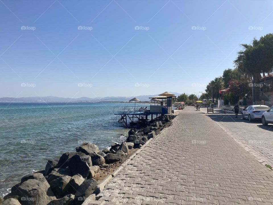 Sunny holidays I’m Turkey. Walk in the cute city and charming streets by the beach in Kusadasi. perfect blue sky and ocean view. Beach and the shore. To travel is to live. Gorgeous tall palm trees.