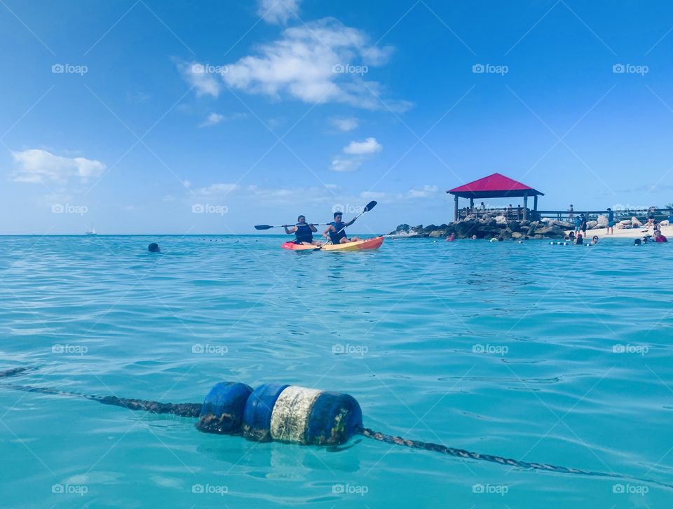 People paddling in kayak on the ocean water by the beach