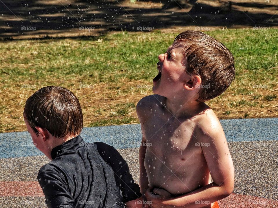 Boys Splashing In Water During Summer