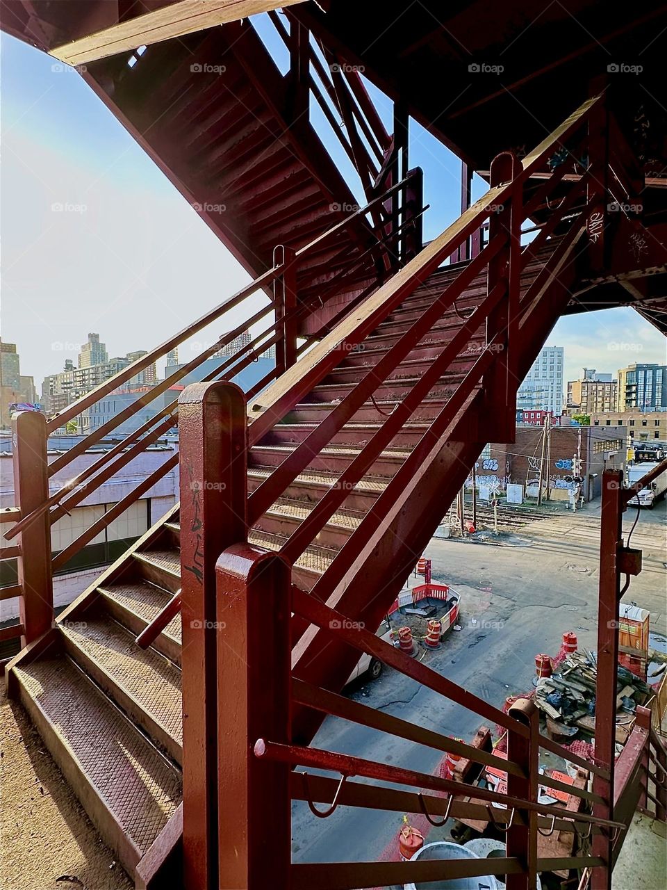 The red metal staircase of the “Pulaski Bridge” at “Newtown Creek” in LIC was built using simple geometric shapes, prime color and highly functional design thereby fulfilling the three tenets of the “Bauhaus” aesthetic. 2024. Hypnotic Productions