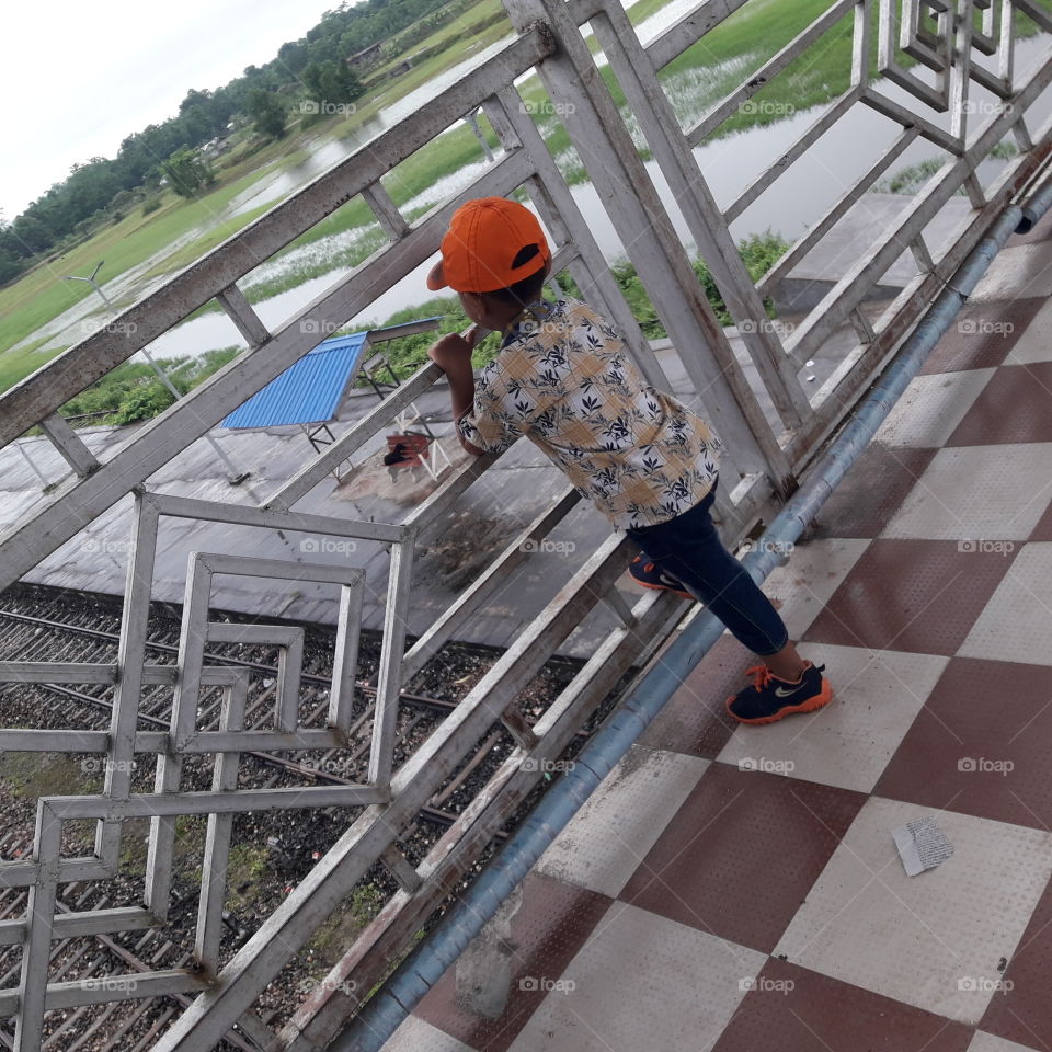 A littile boy injoying the train track from over bridge