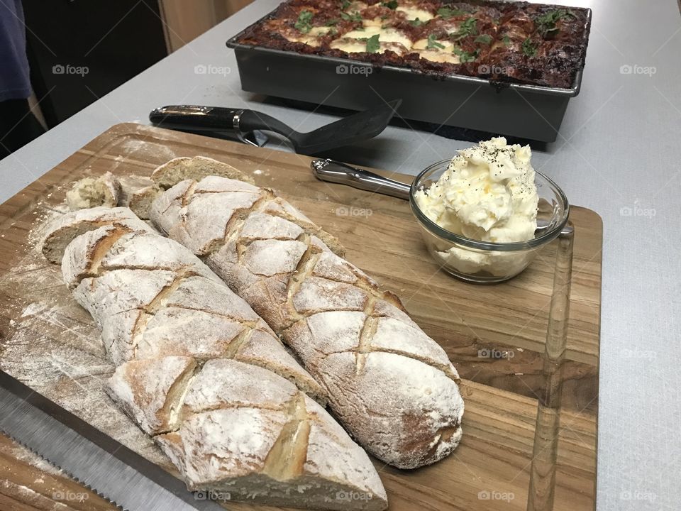 Homemade bread loaves with whipped butter and lasagna. 
