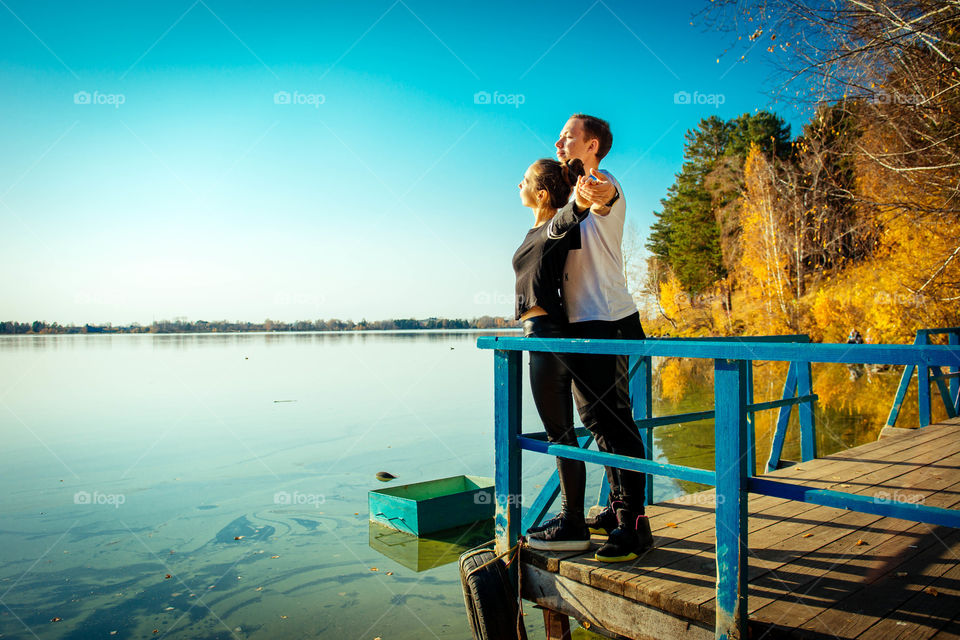 Young couple stretching their arms near sea