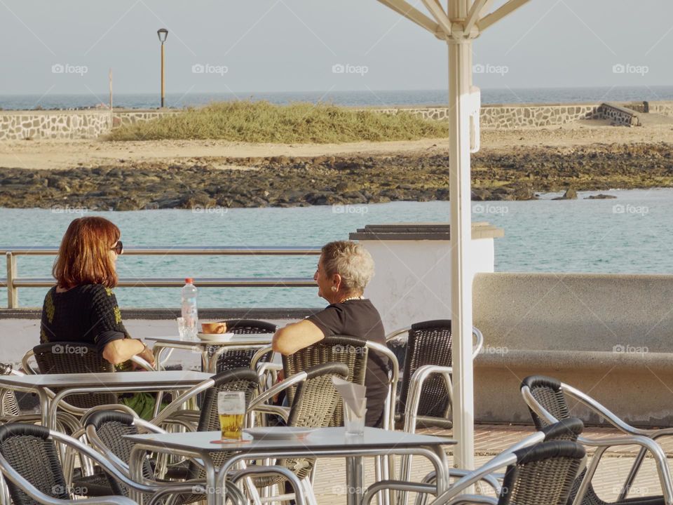 personas en terraza bar tomando algo al atardecer