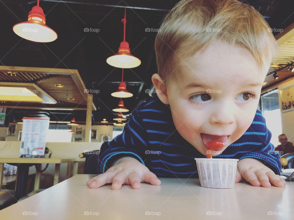 Toddler eating ketchup at a restaurant 