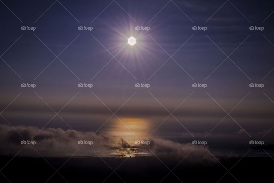 Sun's reflection on a smooth ocean's surface.