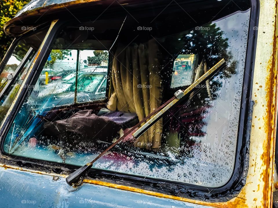 Broken window of an old rusted Volkswagen bus sitting in a parking lot, classic vehicle that has seen better days 
