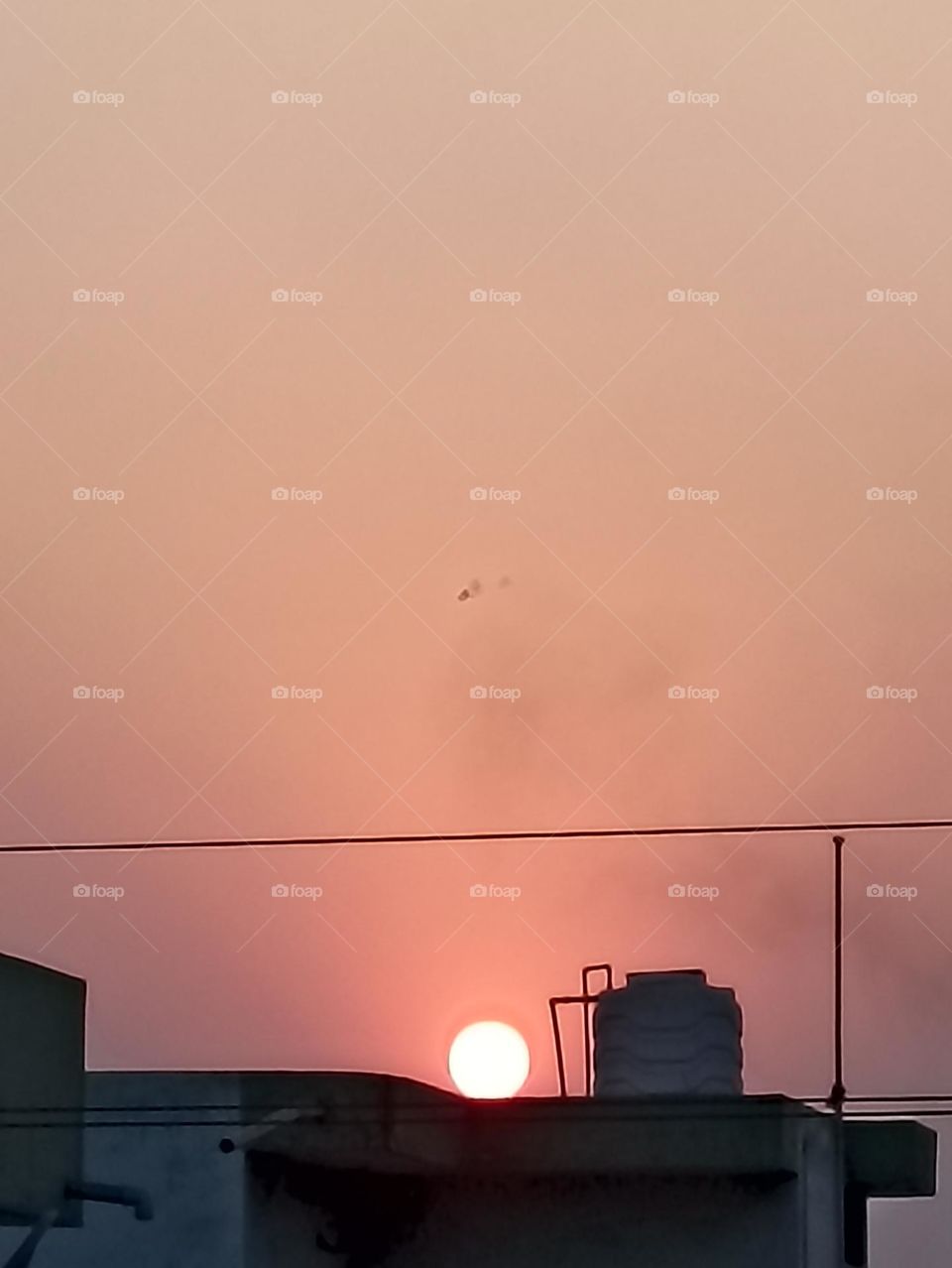 The sun sets with its beauty and smoke from the factory side.