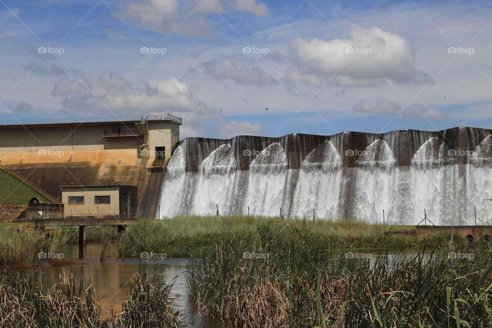Midmar dam wall gently overflowing with green reeds in the foreground