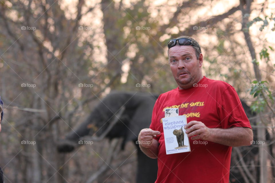 The Elephant Whisperer. Take note of the book title and the elephant behind