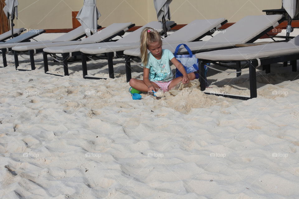 Little blond child playing with the sand 