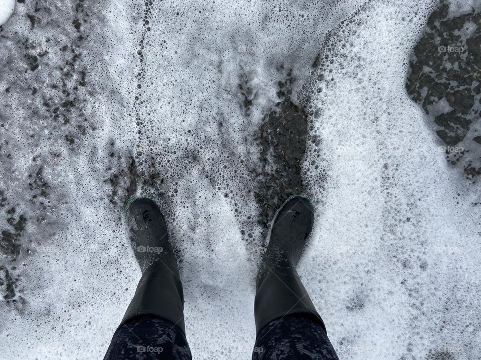 Sea foam gathers around my feet walking in waves