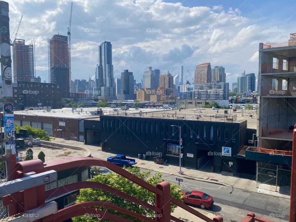 This is a view from atop the red metal staircase of the “Pulaski Bridge” at “Newtown Creek” from the “Greenpoint”, Brooklyn side of the bridge. In the far distance one can see all the way to “Manhattan”. 2023. Hypnotic Productions