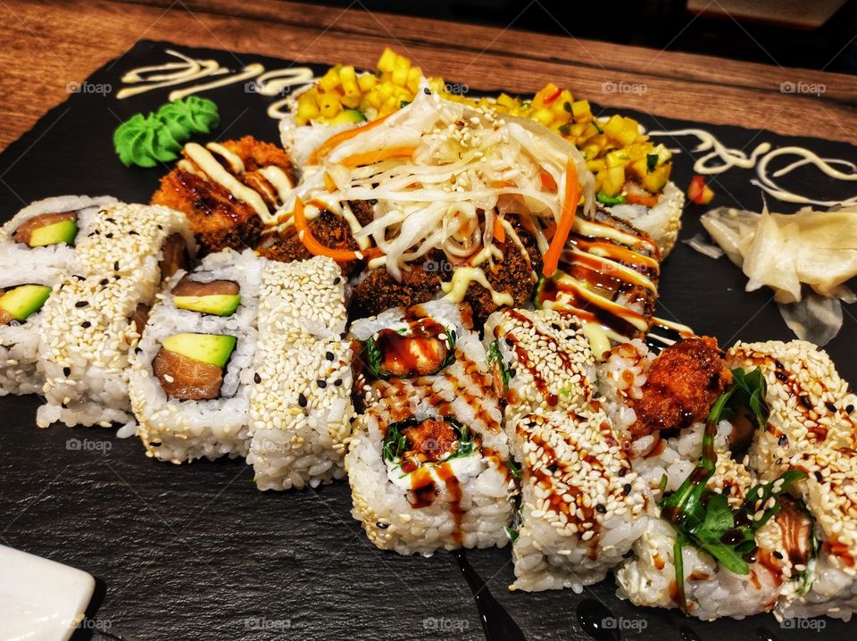A photo of a plate full of colourful sushi with different textures and sauses in a sushi restaurant in Germany
