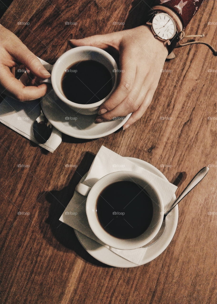 Female hands holding cup of coffee on rustic wooden table