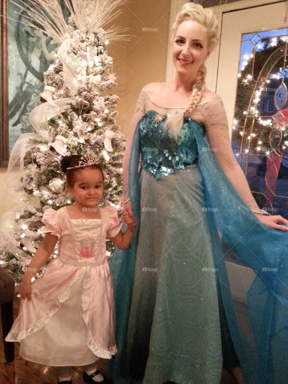 Smiling mother and daughter in front of christmas tree