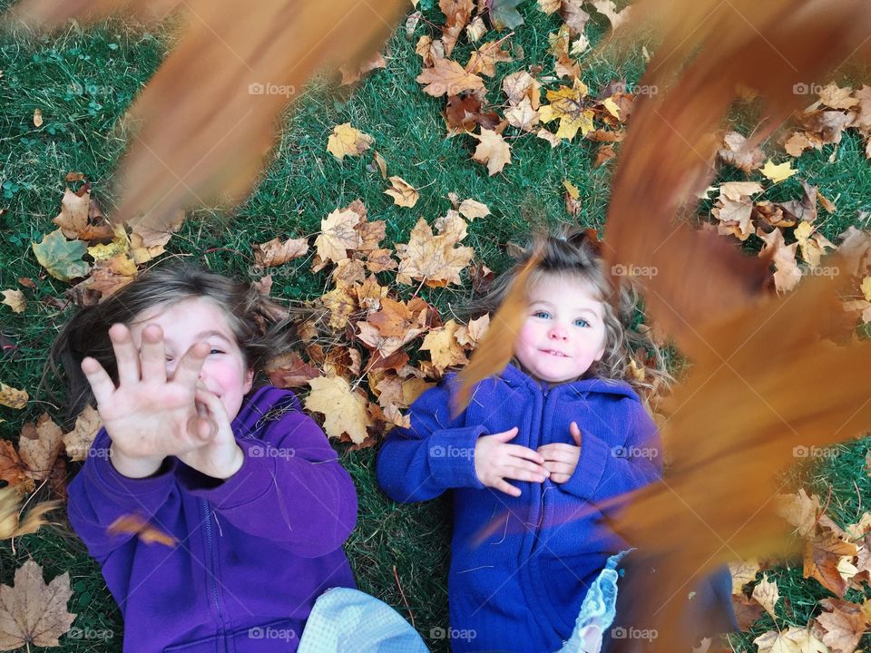 Two sister lying own autumn leaf